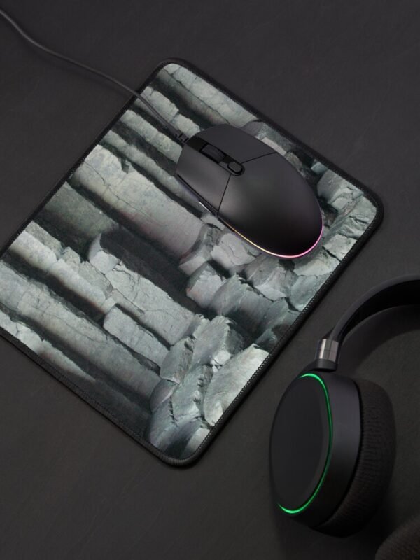 Basalt Columns Mouse Mat with a black mouse sitting on the mat, and black headphones beside the mat