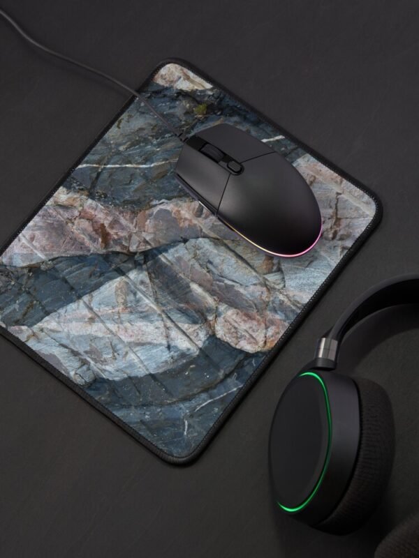 A mouse mat-pad with a closeup image of a multi-coloured rockface on its front