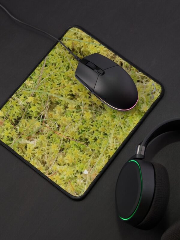 A Bed of Sphagnum Moss mouse mat with a black mouse on it and headphones beside it.