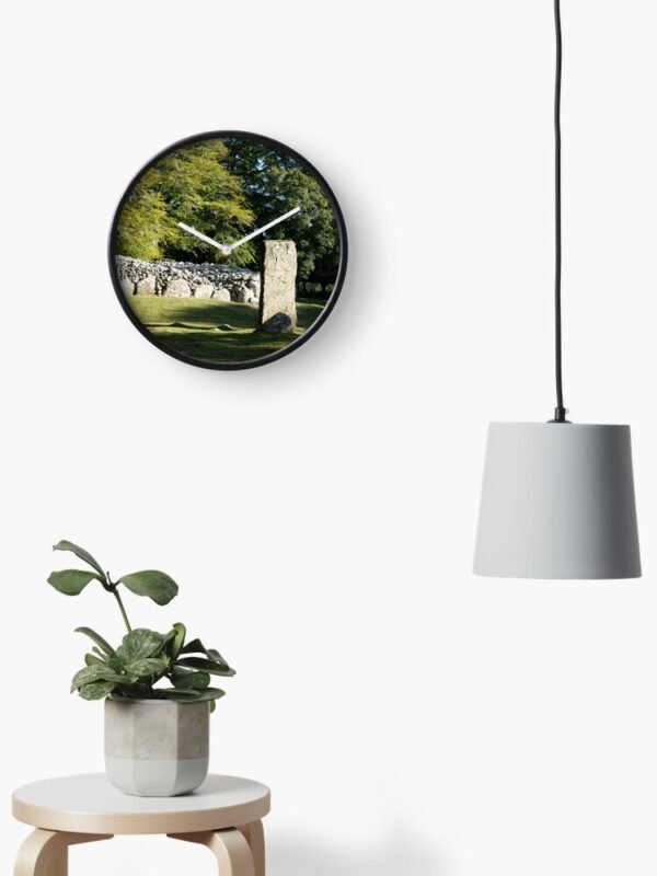 Cairns and Standing Stone Clock on a wall beside a drop light and above a stool with a pot plant
