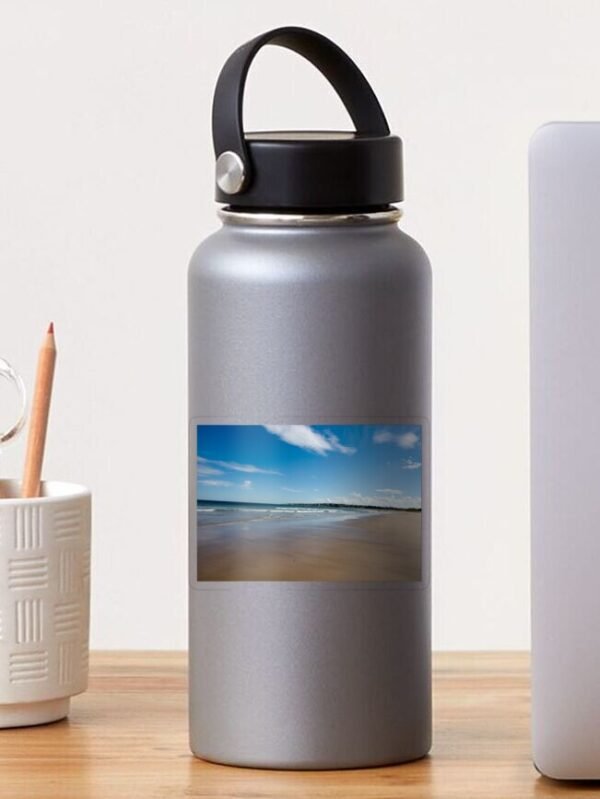 A water bottle which has a transparent sticker with the design of an Expansive Beach At Lossiemouth printed on it.