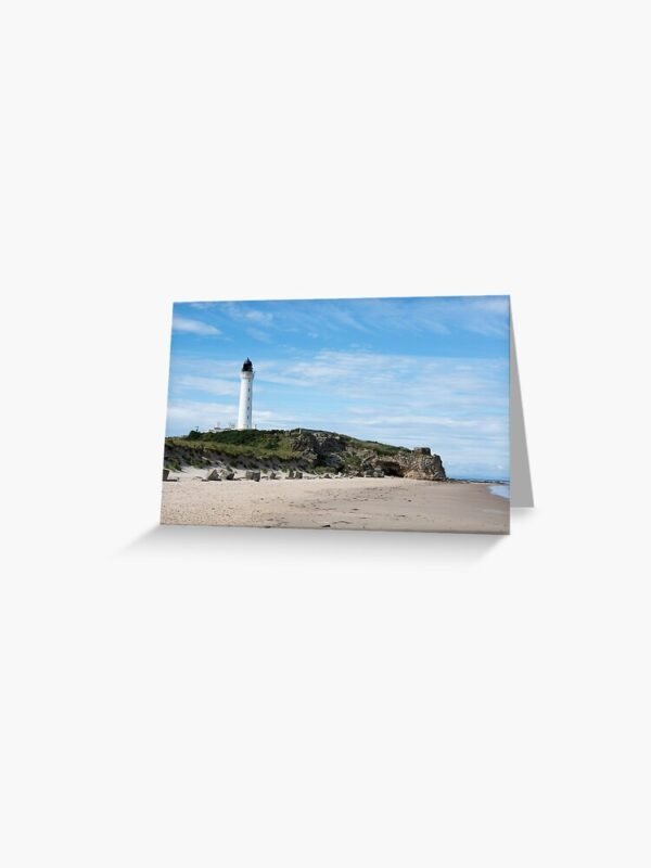 A greeting card with an image of a lighthouse on rocks on a sandy beach