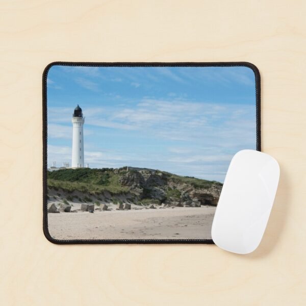 A mouse mat/pad with an image of a lighthouse on rocks on a sandy beach
