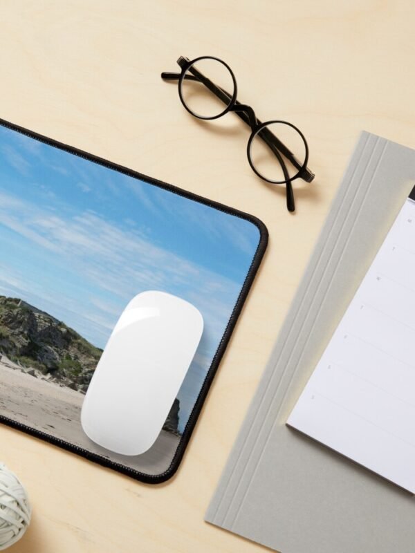 A mouse mat/pad with an image of a lighthouse on rocks on a sandy beach