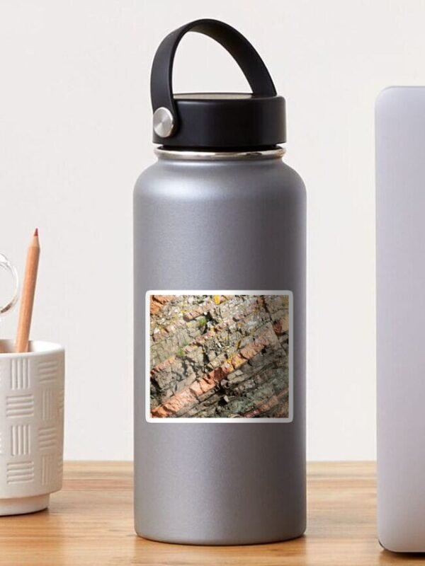 A sticker on a water bottle with the design of a close up image of different coloured layers of rock